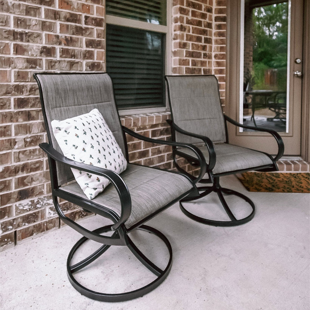 Two gray patio swivel dining chairs with upgraded padded seats, placed on a porch beside a door.