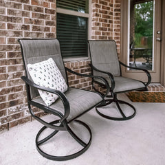 Two gray patio swivel dining chairs with upgraded padded seats, placed on a porch beside a door.