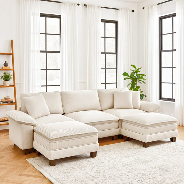 Beige sectional sofa in a living room with large windows and white curtains.