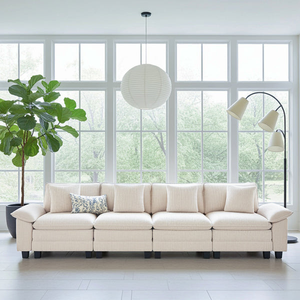 Beige sectional sofa in a bright living room with large windows and a plant.