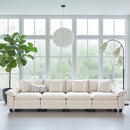 Beige sectional sofa in a bright living room with large windows and a plant.