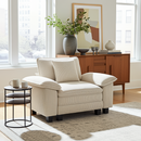 Beige armchair in a living room with a wooden sideboard and decorative items.