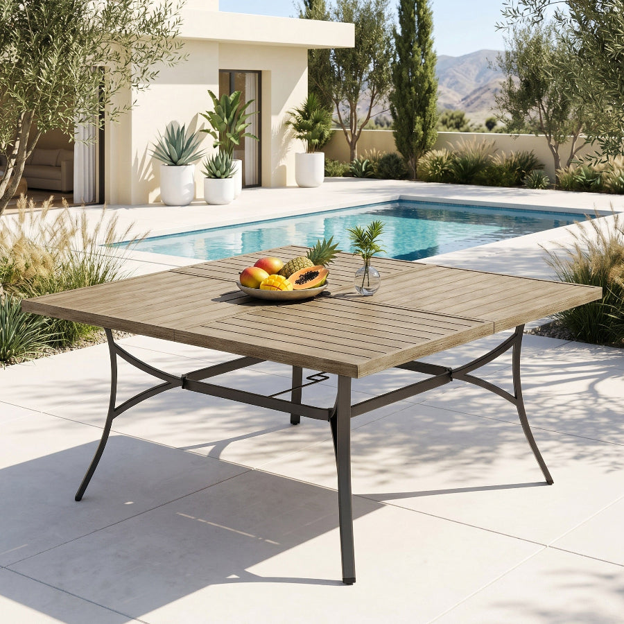 Wooden outdoor dining table with fruit bowl in a poolside setting