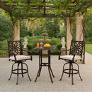 cast aluminum barstools set with two counter-height chairs and a table under a pergola with a fountain in the background.