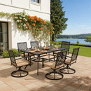 Outdoor dining set with table and chairs on a patio by a house with flowers and a lake view.