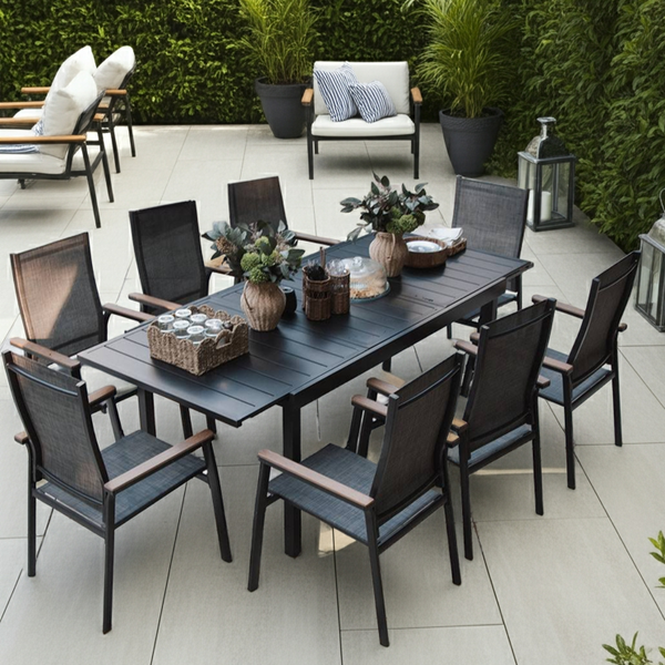Outdoor patio set with an expandable table and chairs on a tiled patio surrounded by greenery
