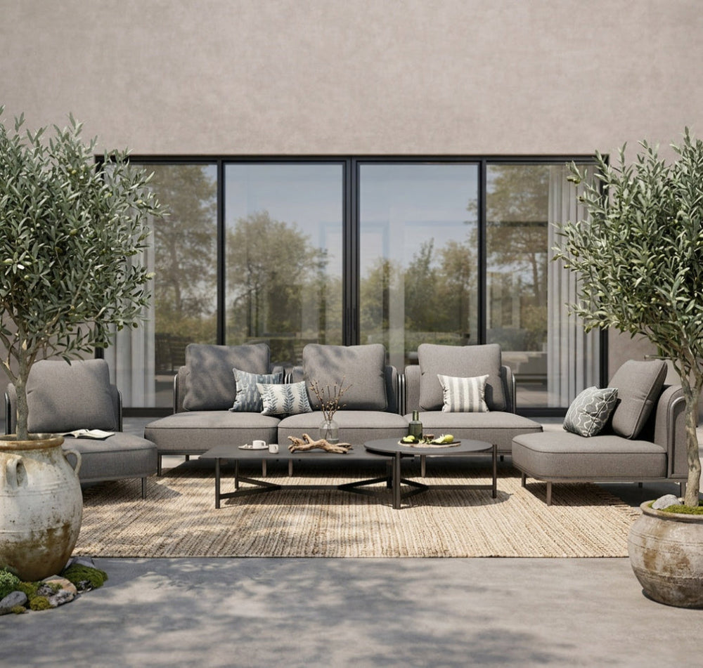 Outdoor patio set with gray sofa, coffee table, and decorative pillows in a modern setting.